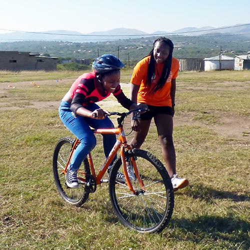 english student teaching african student to ride a bike