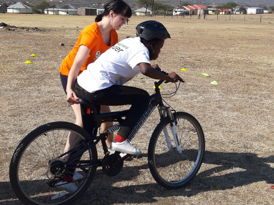 Gryphons Abroad Student helping child to ride a bike