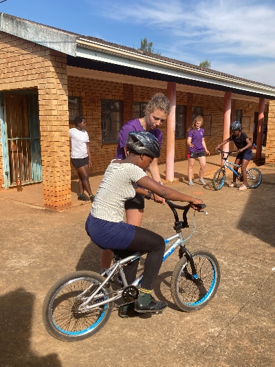 Volunteer helping school kid ride a bike