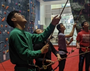 Photo of a person belaying another person rope climbing