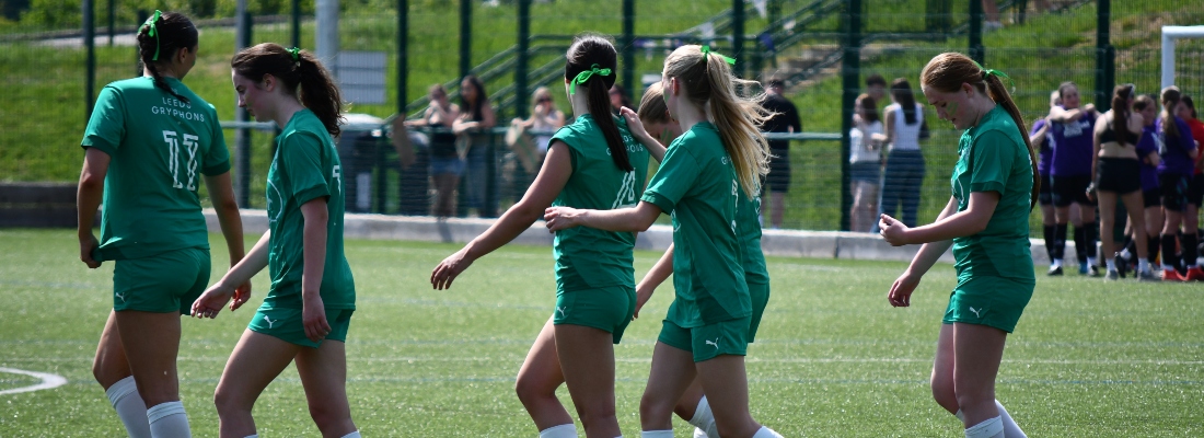 group of women in football kit celebrating on the pitch