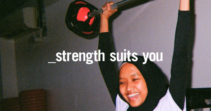 Young woman lifting barbell above her head